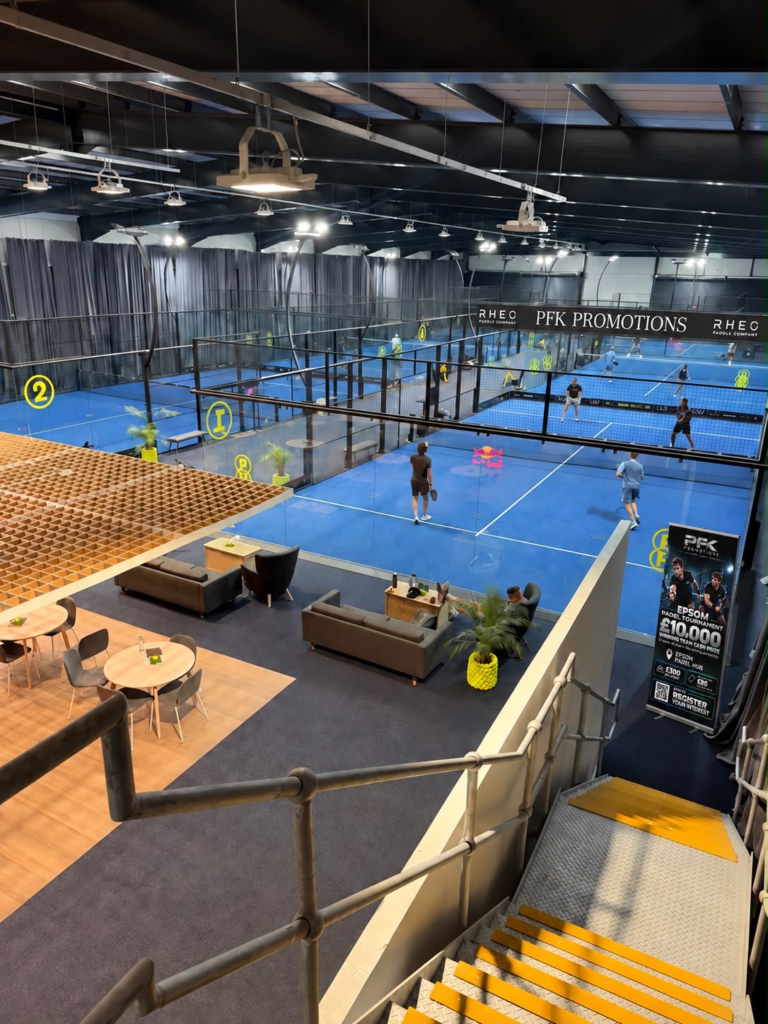Players on the blue padel courts at the venue, with the PFK Promotions banner along the back wall